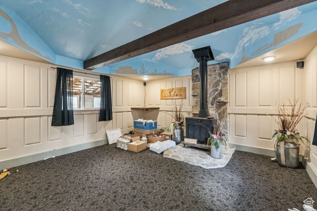 Carpeted living area with a wood stove and beamed ceiling