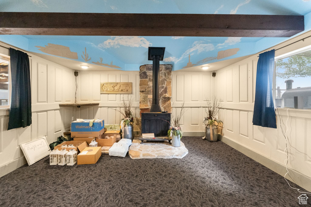 Interior space with carpet floors, a wood stove, and beamed ceiling