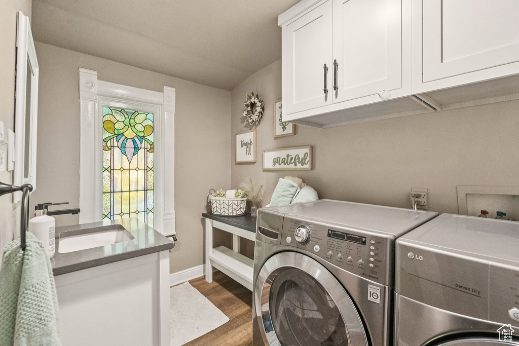 Laundry area featuring washing machine and dryer, cabinet space, and wood finished floors