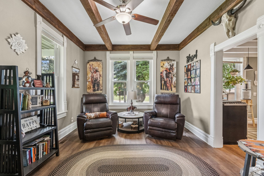 Sitting room with plenty of natural light, ceiling fan, wood finished floors, and beam ceiling