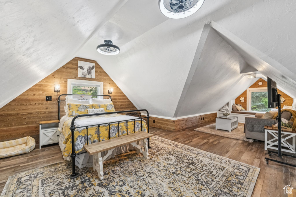 Bedroom with wooden walls, lofted ceiling, and hardwood / wood-style flooring