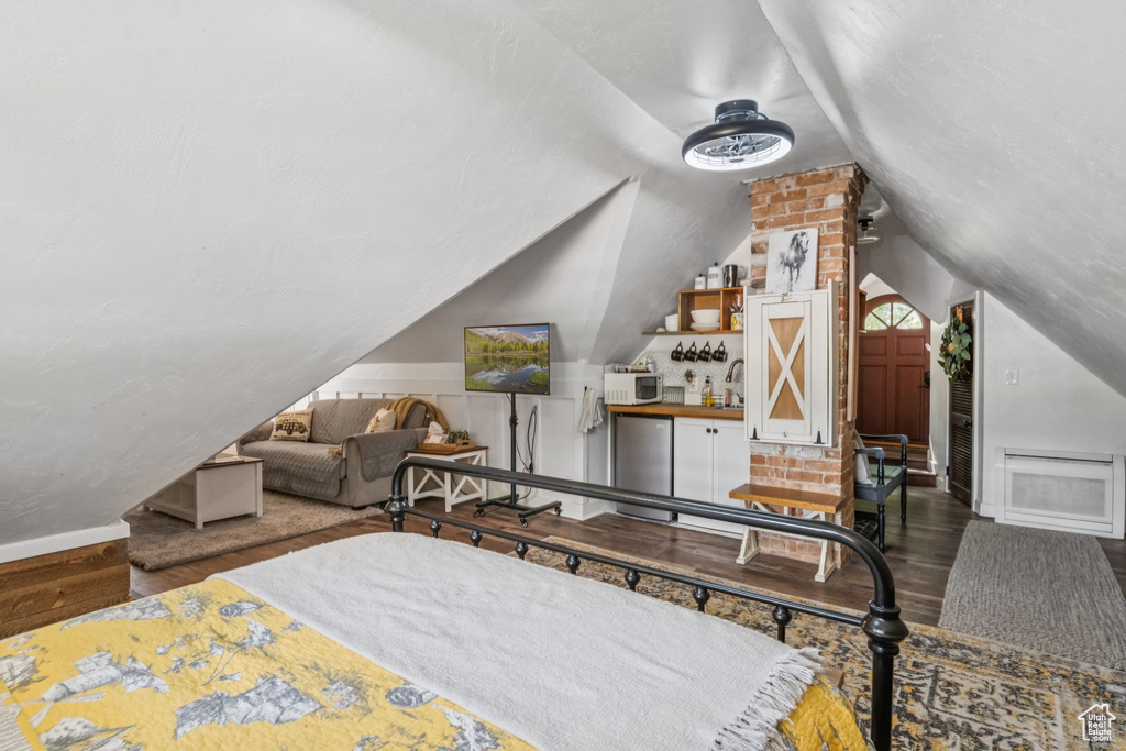 Bedroom with wood finished floors, lofted ceiling, and freestanding refrigerator