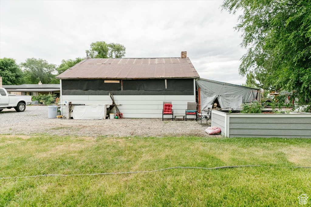 Back of house featuring a lawn, a metal roof, and a chimney