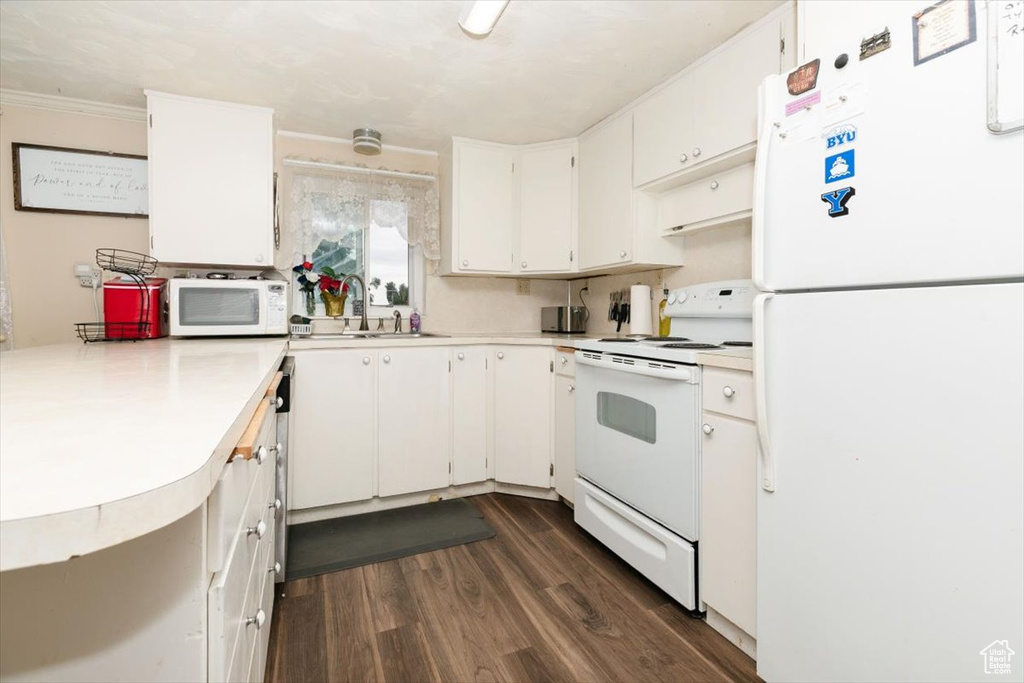 Kitchen with white appliances, light countertops, dark wood-style flooring, and white cabinetry
