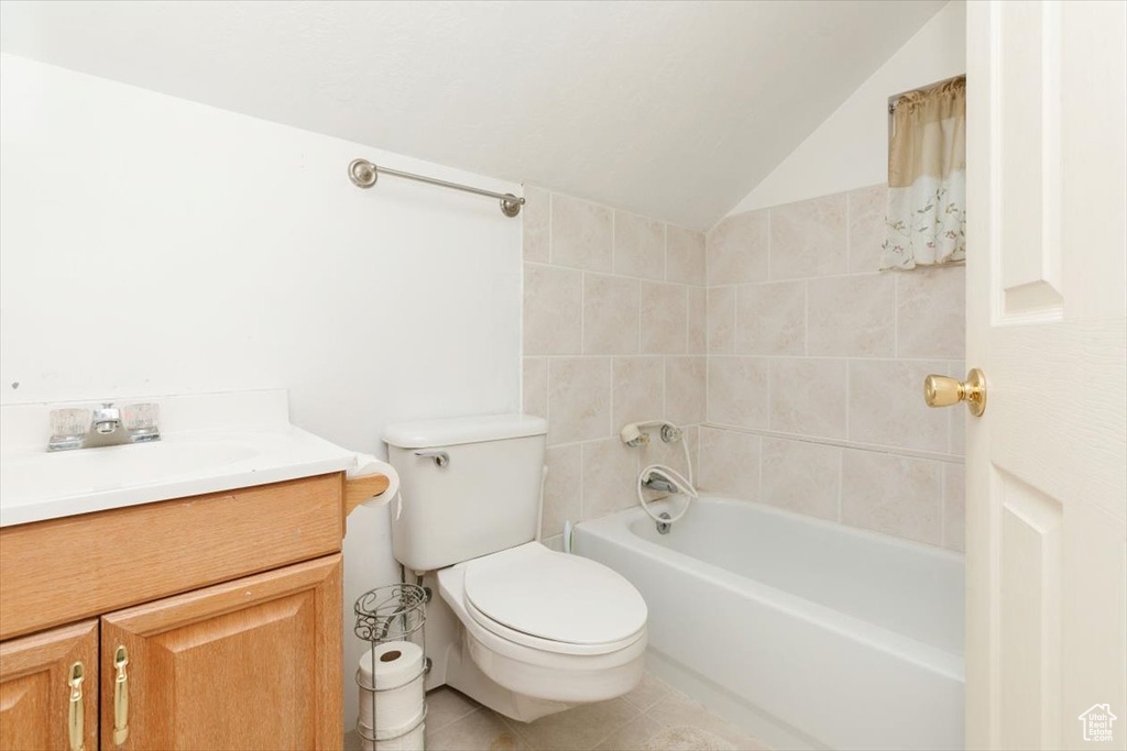 Bathroom with tile patterned floors, vaulted ceiling, and vanity