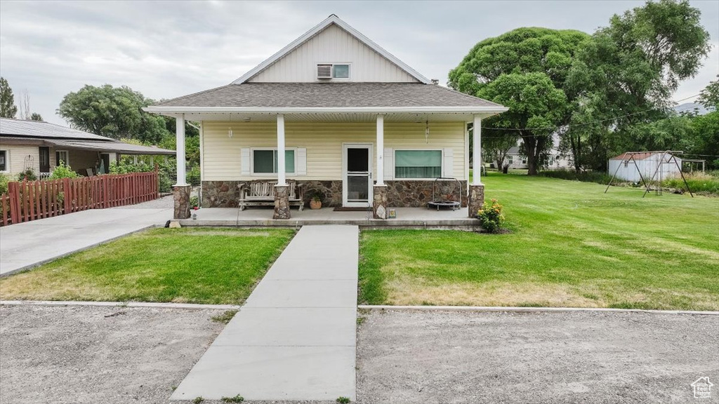 View of front of home with a porch, stone siding, and a shingled roof