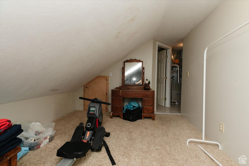 Workout area featuring lofted ceiling, carpet, and a textured ceiling