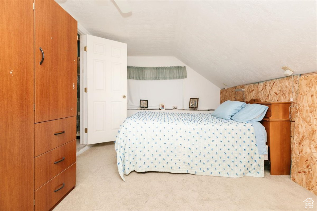 Bedroom featuring light colored carpet, lofted ceiling, and a ceiling fan