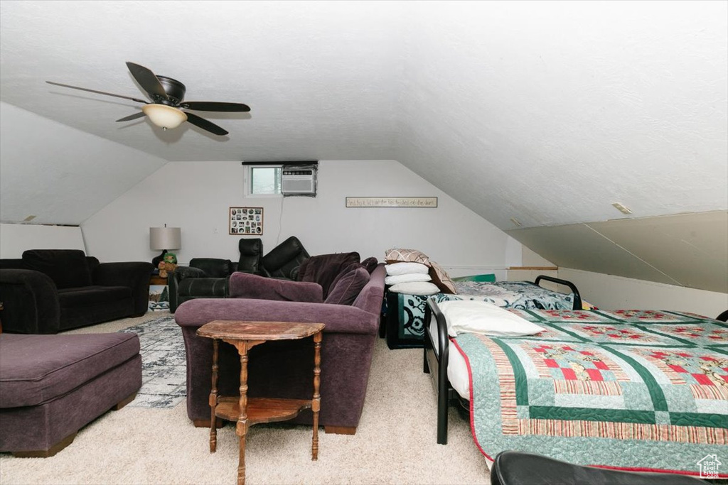 Carpeted bedroom with lofted ceiling, a ceiling fan, and a wall mounted air conditioner