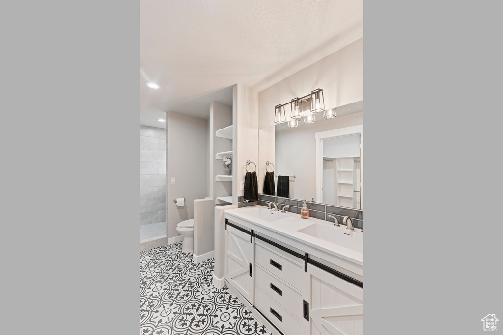 Full bathroom featuring double vanity, tiled shower, tile patterned flooring, and recessed lighting