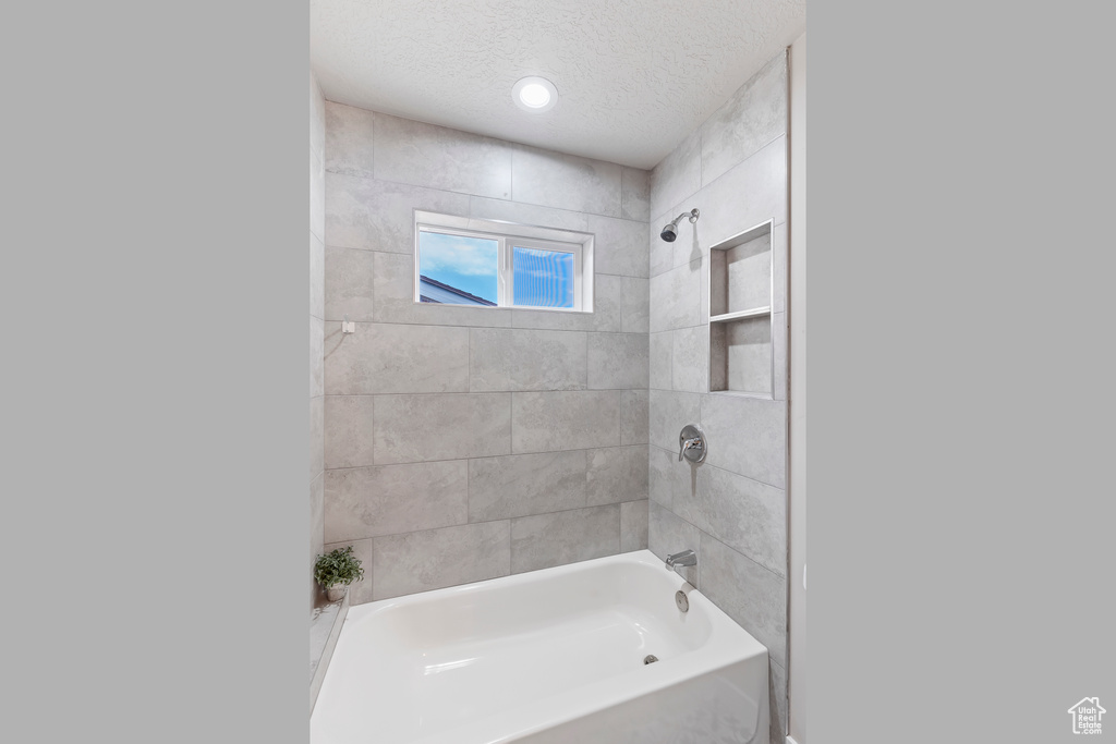 Full bath featuring a textured ceiling and bathtub / shower combination
