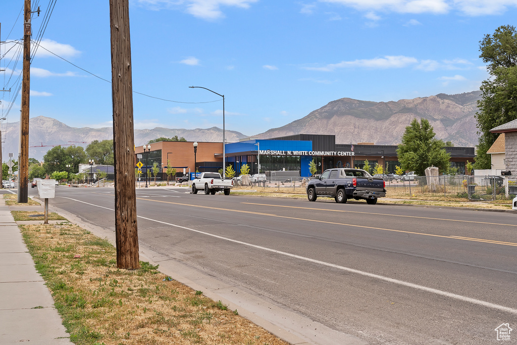 View of asphalt street featuring a mountain view, street lighting, sidewalks, and curbs