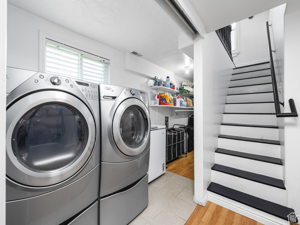 Laundry room with washer and clothes dryer and light tile patterned flooring