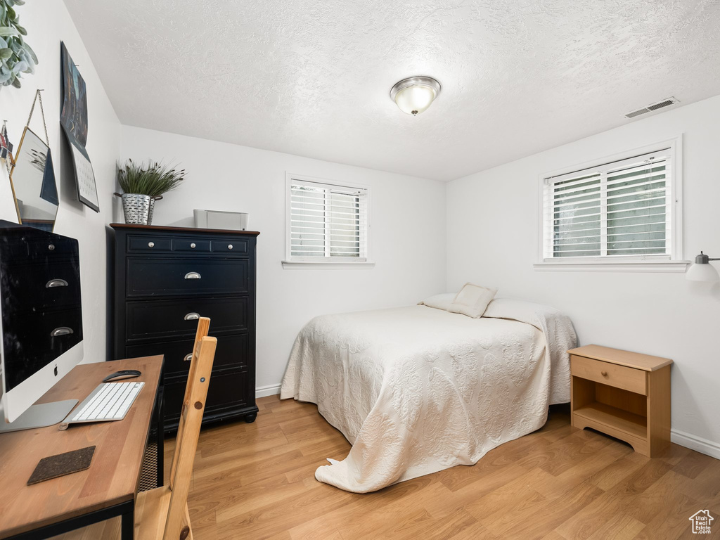 Bedroom with light wood-type flooring and a textured ceiling