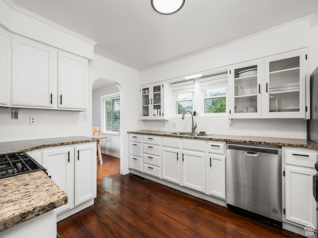 Kitchen featuring dishwasher, arched walkways, dark wood finished floors, glass insert cabinets, and white cabinets
