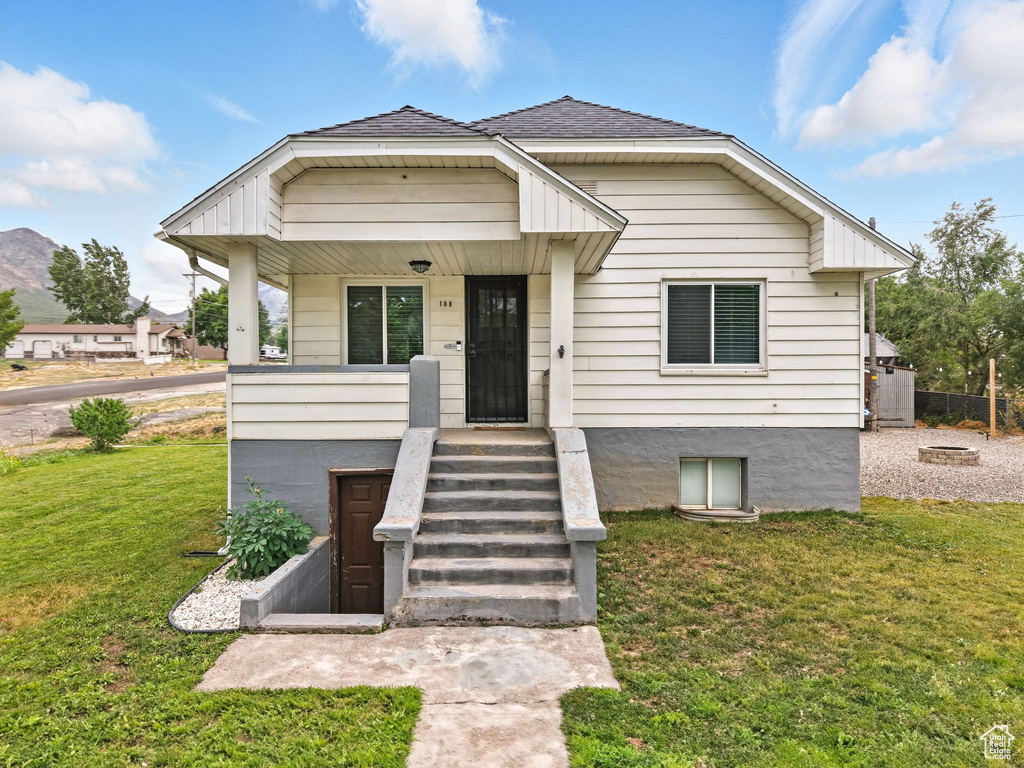 View of front of home with a front yard, a porch, and a shingled roof