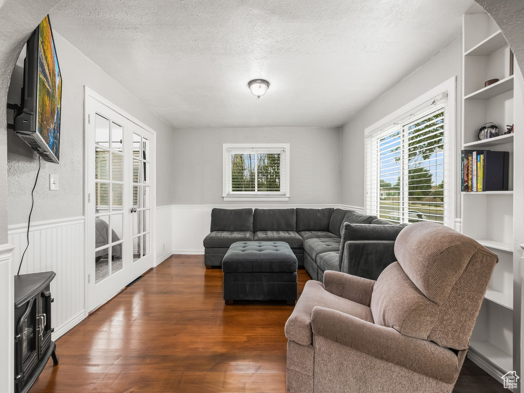 Living area featuring a wainscoted wall, plenty of natural light, wood finished floors, a textured ceiling, and built in features