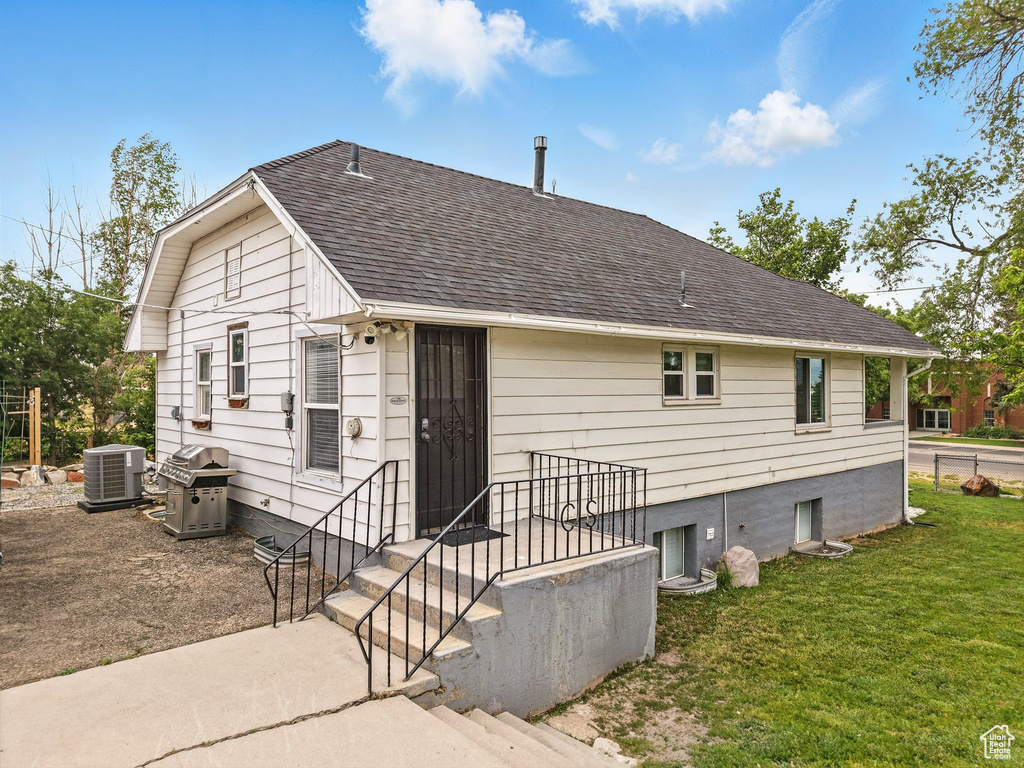 Rear view of house with a shingled roof and a lawn