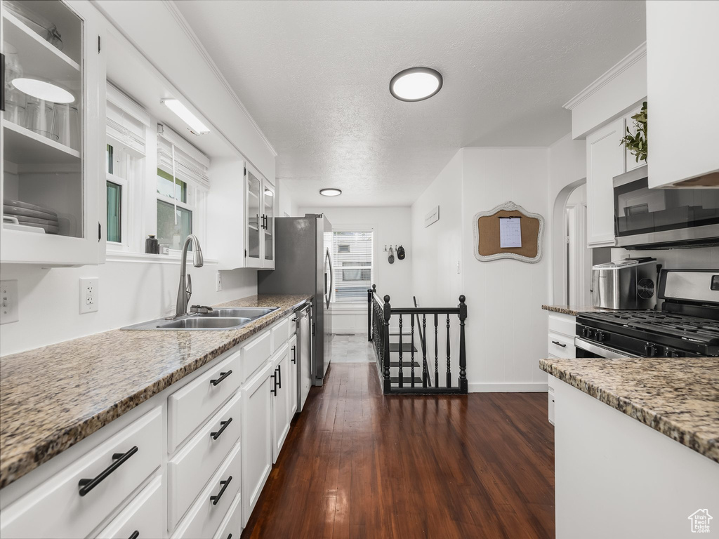 Kitchen featuring appliances with stainless steel finishes, white cabinets, glass insert cabinets, and a textured ceiling