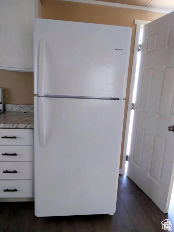 Kitchen with freestanding refrigerator, light countertops, white cabinetry, and dark wood finished floors