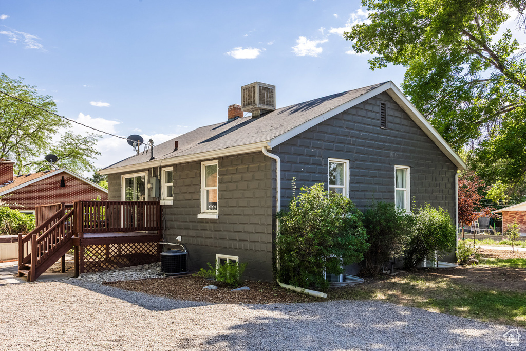 View of property exterior featuring a deck, a chimney, and a shingled roof