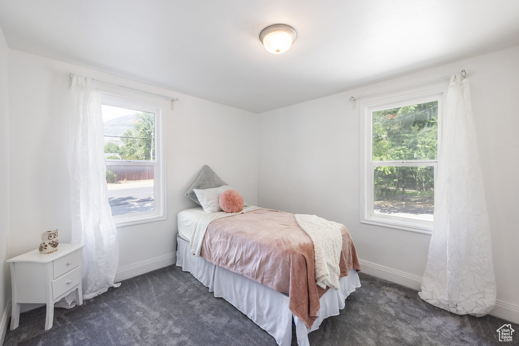 Bedroom featuring dark carpet and multiple windows