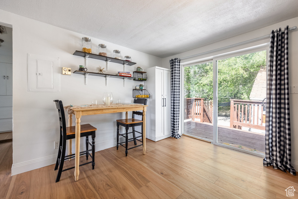 Kitchen with wood finished floors, open shelves, a textured ceiling, and electric panel