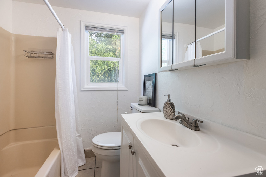 Full bath featuring vanity, tile patterned floors, shower / tub combo, and a textured wall
