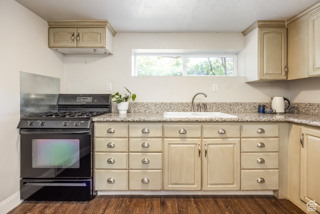 Kitchen featuring black range with gas cooktop, light brown cabinetry, and dark wood-style floors