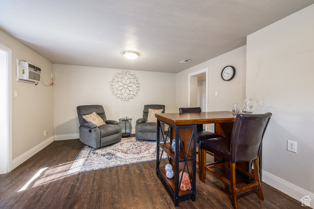 Dining area with wood finished floors and an AC wall unit