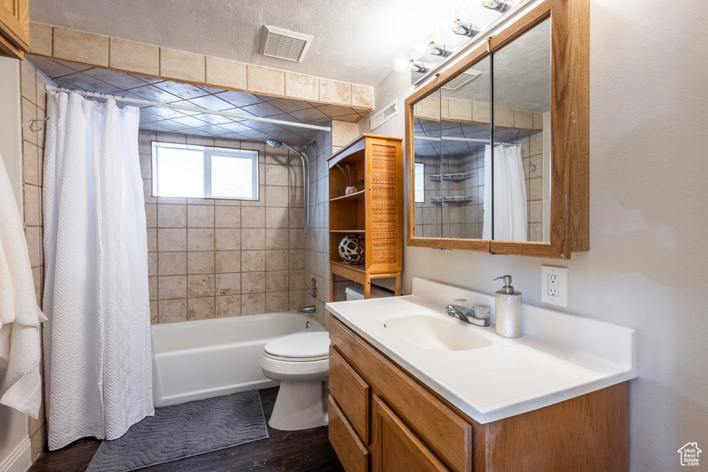 Full bath with vanity, shower / bath combo, and wood finished floors