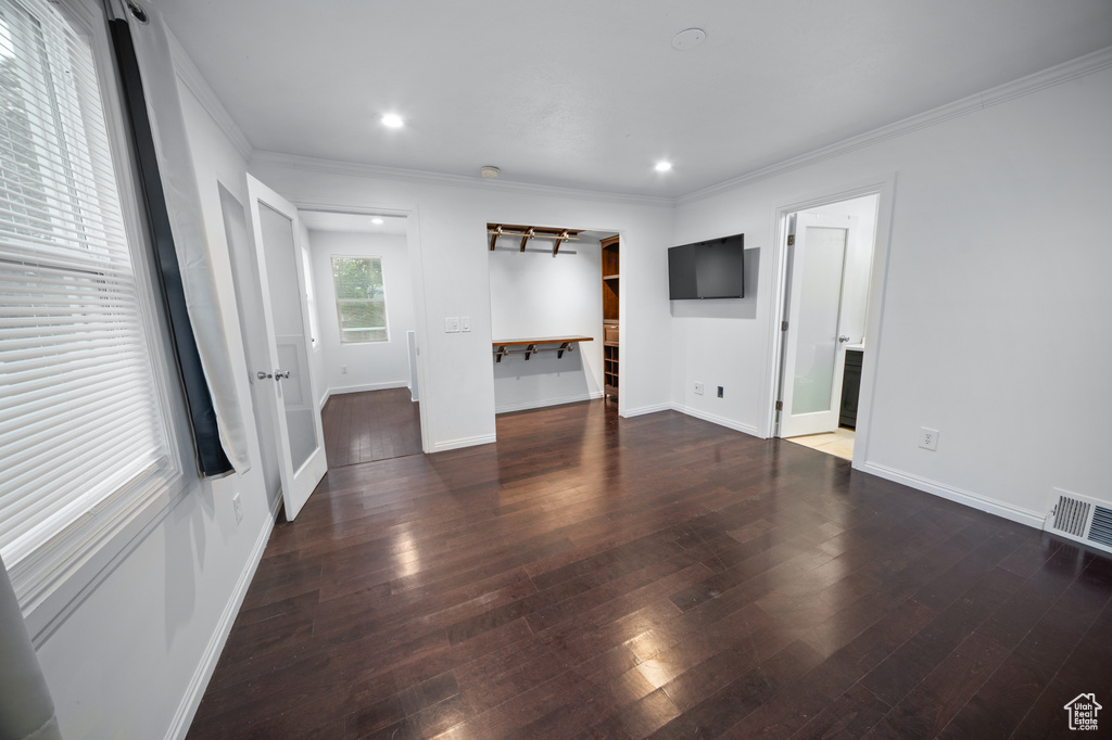Unfurnished living room featuring wood-type flooring, crown molding, and recessed lighting