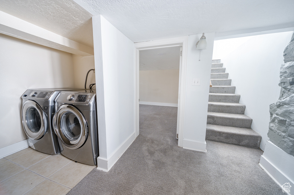 Laundry area with washing machine and dryer, a textured ceiling, and light carpet