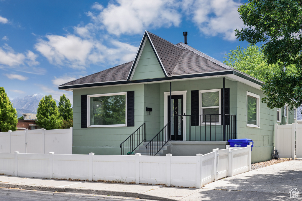Bungalow featuring roof with shingles, a fenced front yard, and a mountain view