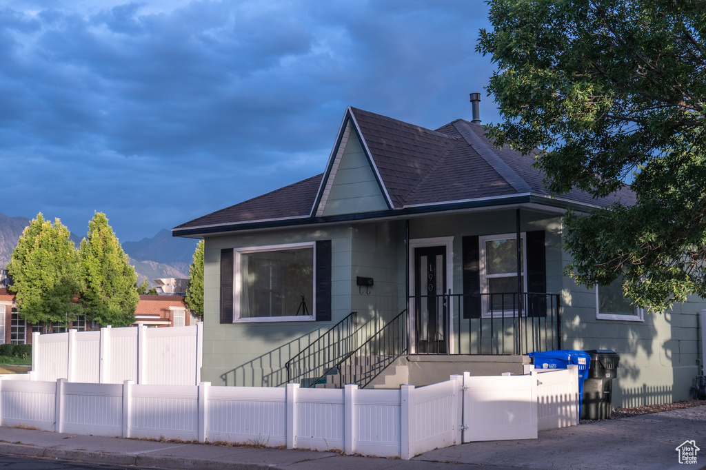 Bungalow-style house featuring roof with shingles, a fenced front yard, and a mountain view
