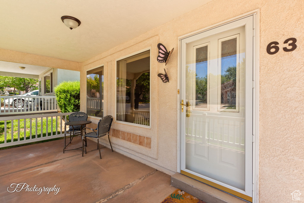 Doorway to property with stucco siding and covered porch