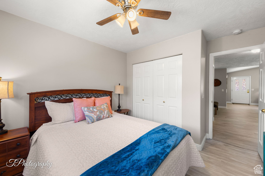 Bedroom with light wood-style floors, a closet, ceiling fan, and a textured ceiling