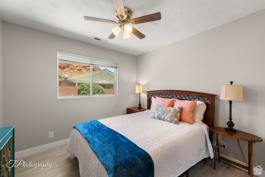 Bedroom featuring wood finished floors, ceiling fan, and a textured ceiling