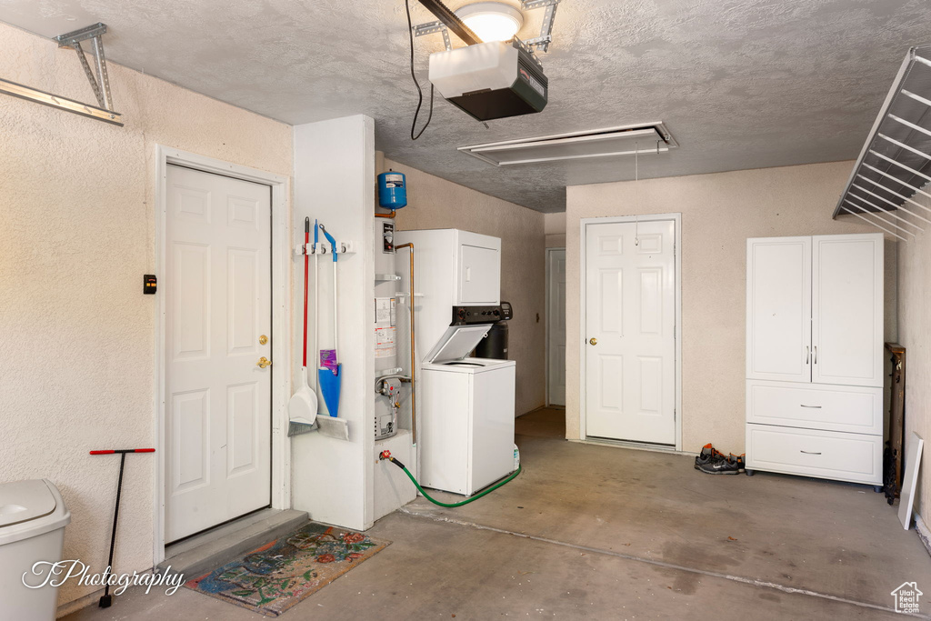Garage featuring estacked washer and dryer, a garage door opener, and a textured wall