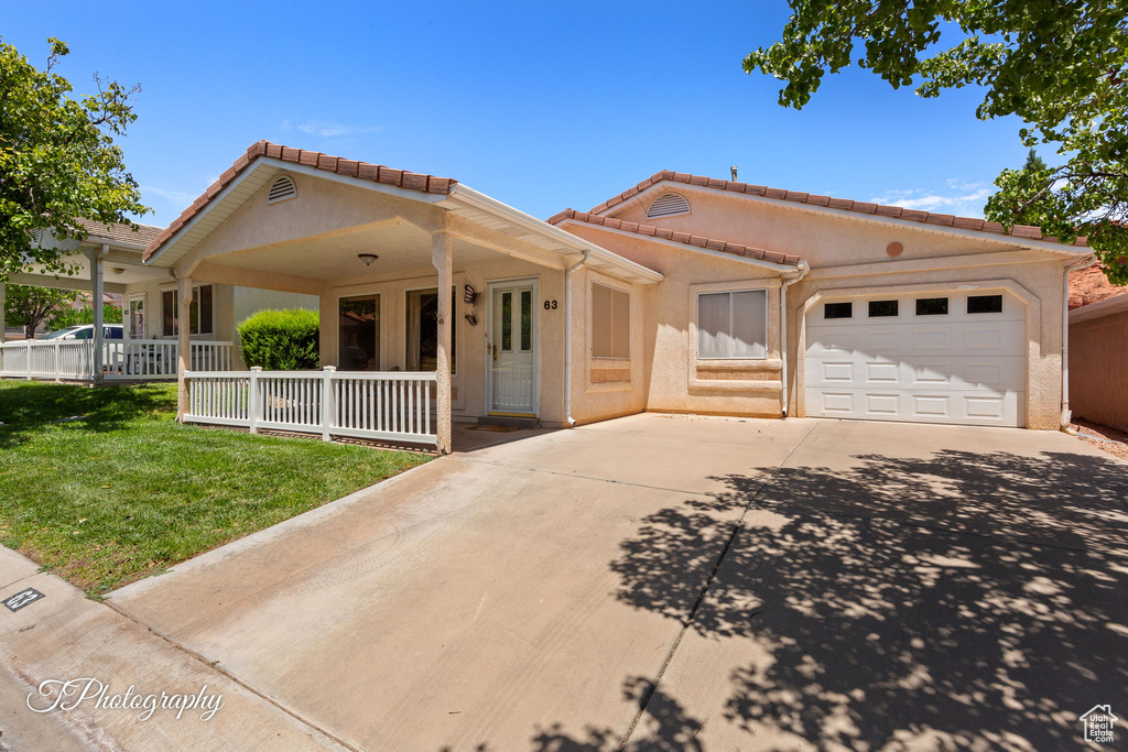 View of front facade with concrete driveway, a porch, a garage, and stucco siding