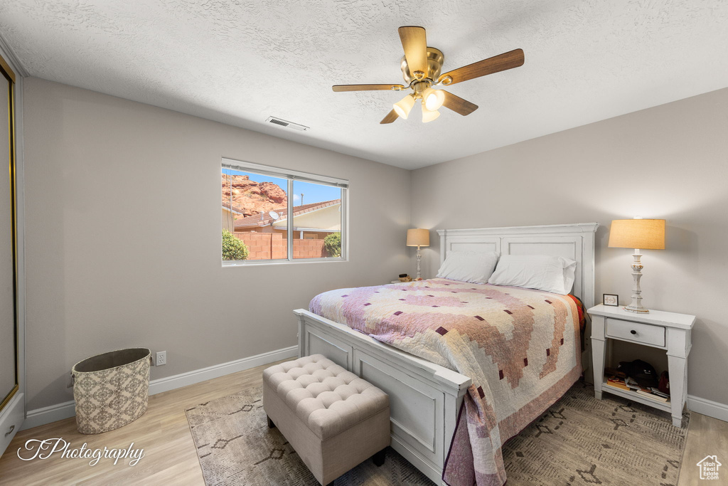 Bedroom with wood finished floors, ceiling fan, and a textured ceiling