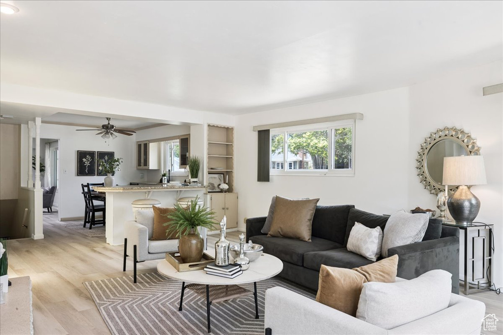Living room featuring ceiling fan, plenty of natural light, and light wood-style flooring