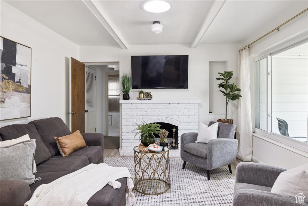 Carpeted living room with beam ceiling and a brick fireplace