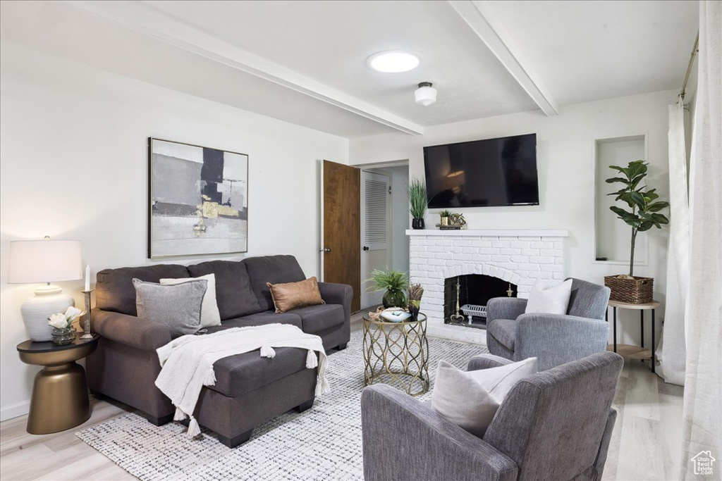 Living room with beamed ceiling, wood finished floors, and a fireplace