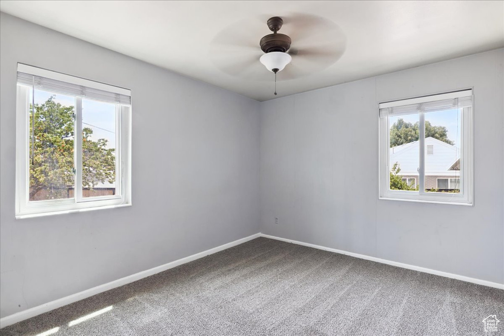 Carpeted empty room with healthy amount of natural light and a ceiling fan
