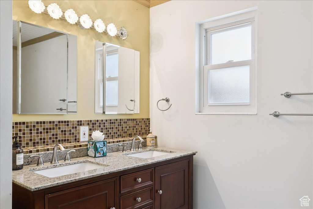 Bathroom featuring double vanity and decorative backsplash