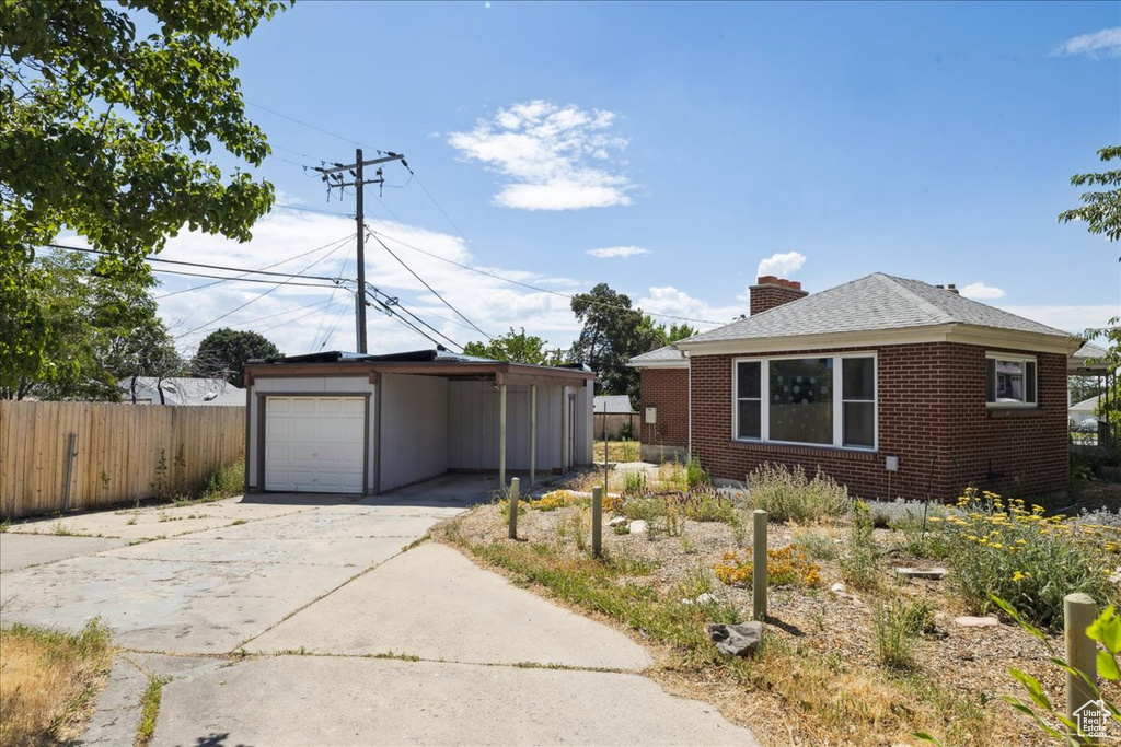 View of front of property featuring driveway, a chimney, brick siding, and a shingled roof