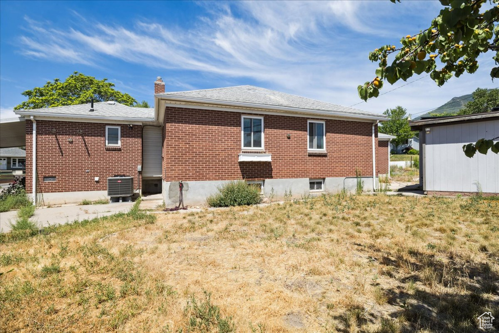 Back of house featuring brick siding and a chimney