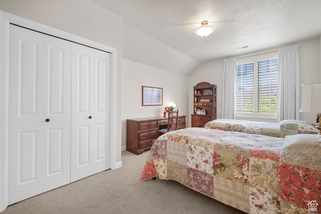 Bedroom with carpet floors, vaulted ceiling, and a closet