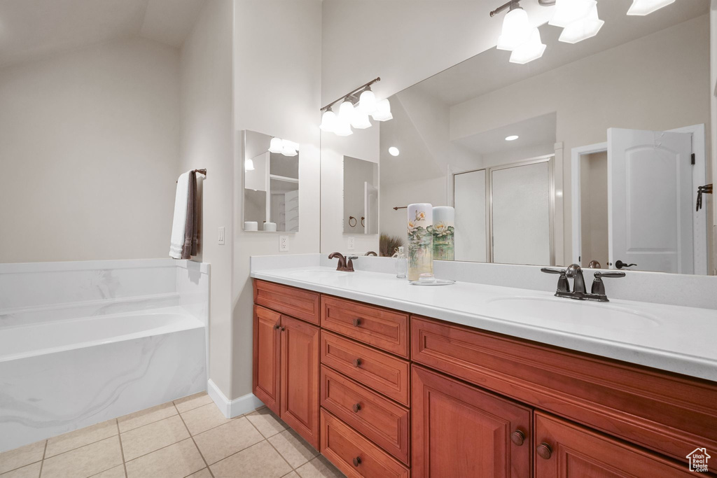 Bathroom with a bath, tile patterned flooring, double vanity, a shower stall, and vaulted ceiling